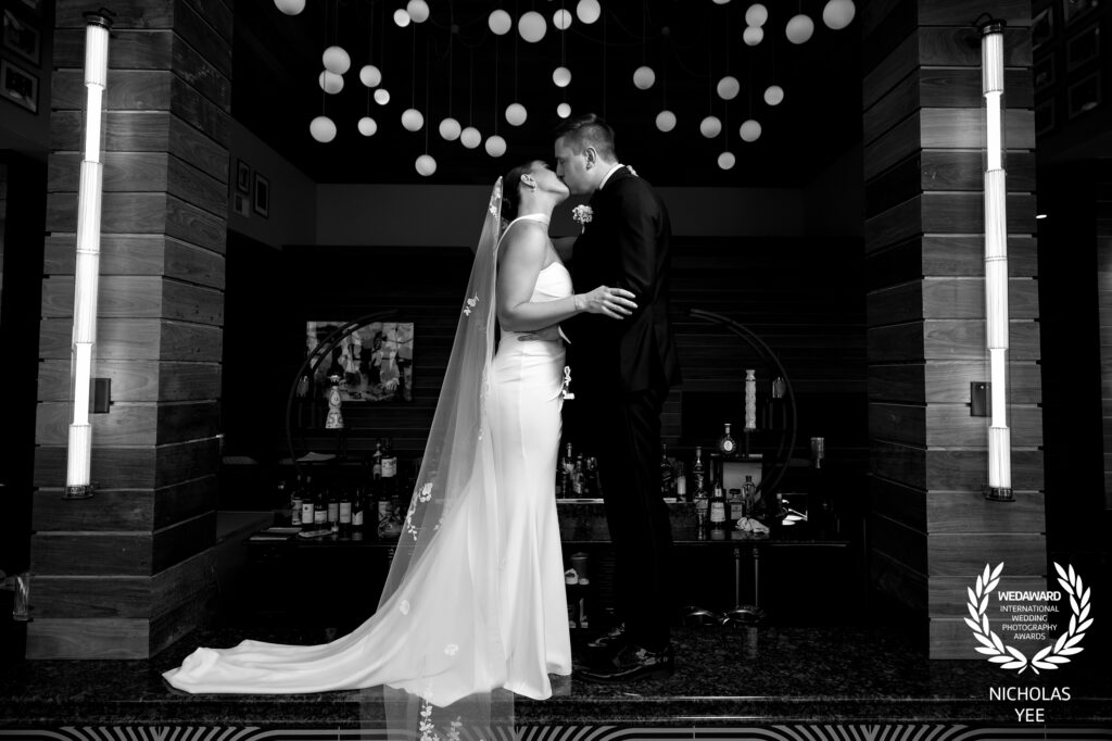 A black-and-white portrait of a couple sharing a kiss, highlighting the intimate connection, skillfully captured by an award-winning wedding photographer.