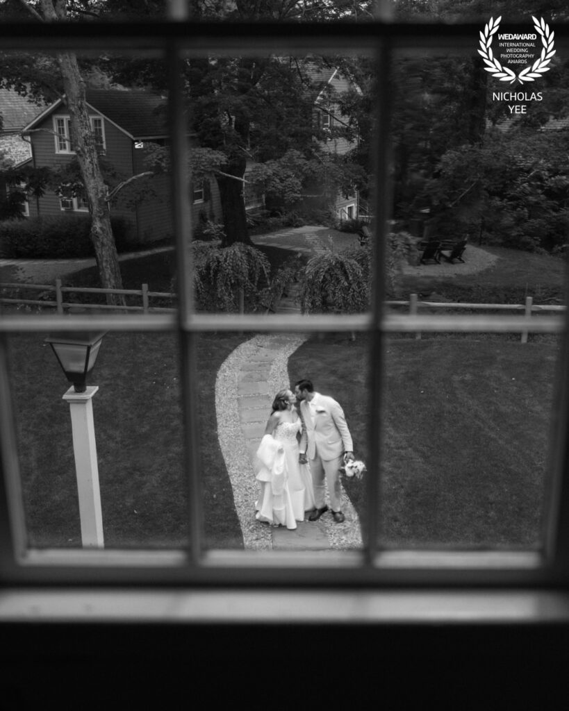 Award-winning black-and-white wedding portrait of a couple framed through a window by Nicholas Yee Photography.